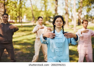 Peaceful Asian qigong instructor holding hands in front of herself - Powered by Shutterstock