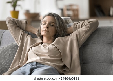 Peaceful attractive mature woman relaxing on sofa with eyes closed, lean back with hands behind head, felt asleep, relieving fatigue, breath fresh air inside modern living room, enjoy weekend at home - Powered by Shutterstock