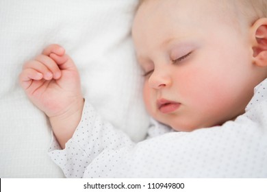 Peaceful baby lying on a bed while sleeping in a bright room