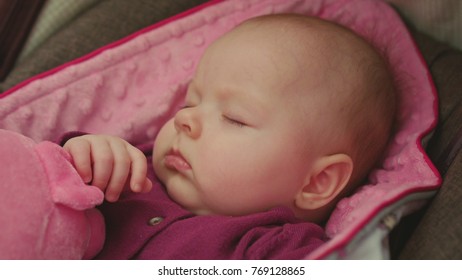 Peaceful Baby Sleeping In A Car Seat On Pink Blanket Holding Pink Toy