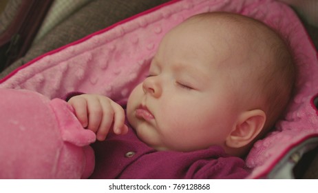 Peaceful Baby Sleeping In A Car Seat On Pink Blanket With Pink Toy