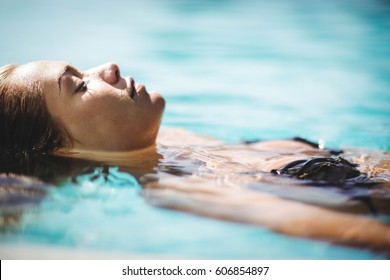 Peaceful blonde floating in the pool with eyes closed