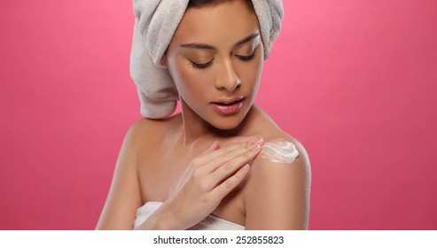 Peaceful brunette applying some cream on her arm