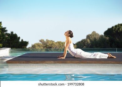 Peaceful brunette in cobra pose poolside on a sunny day at the spa - Powered by Shutterstock