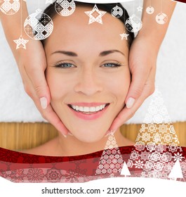 Peaceful brunette enjoying a facial massage against christmas themed frame