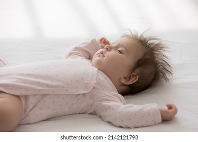 Peaceful Calm Sleepy Cute Baby Girl Wearing Pink Bodysuit, Sleeping On Bed. Beautiful Few Month Infant Kid Resting On Pale Sheet, Linen. Childcare, Bedtime, Daily Routine Concept