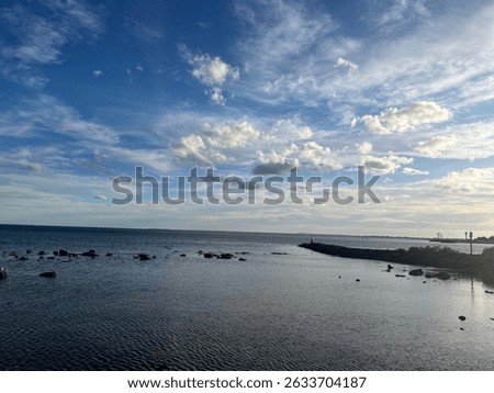 Peaceful coastal inlet with calm reflective waters, scattered rocks, and a pastel-toned sky during golden hour. Perfect for seascapes, evening tranquility, nature backgrounds, and oceanview lifestyle 
