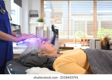 Peaceful elderly woman receiving reiki healing therapy on head. Alternative therapy treatment and Reiki technique concept - Powered by Shutterstock