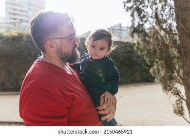 A Peaceful Father Holding Up His Little Son In Park