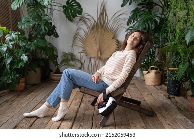 Peaceful Girl Florist Relax On Comfortable Chair With Eyes Closed Sleeping Resting In Greenhouse After 3d Gaming Or Online Shopping. Female Feel Fatigue Fall Asleep After Using Virtual Reality Headset