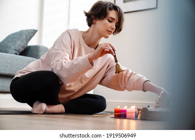 Peaceful Girl Ringing Bell While Sitting At Home Shrine Indoors