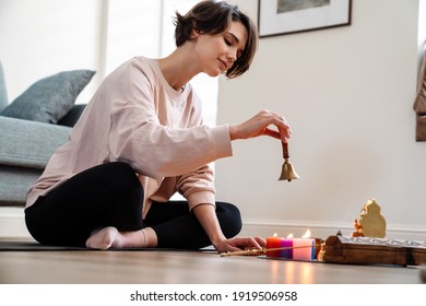 Peaceful Girl Ringing Bell While Sitting At Home Shrine Indoors