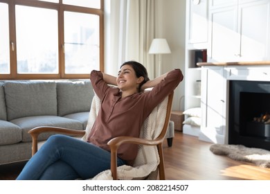 Peaceful happy young indian woman sitting in comfortable armchair, enjoying break pause relaxation time on weekend in modern living room. Happy millennial female homeowner resting alone indoors. - Shutterstock ID 2082214507