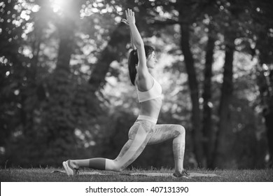 Peaceful and healthy. Black and white shot of a sporty young female practising yoga balancing in a warrior asana at the local park.