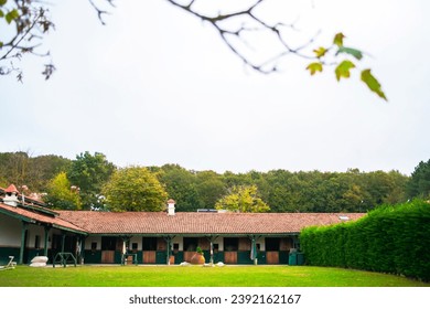 A peaceful horse stable surrounded by lush green grass invites a serene scene where equine companions graze contentedly. 