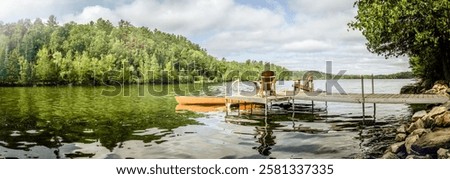 A peaceful lakeside dock featuring two Adirondack chairs overlooking calm waters, surrounded by lush greenery. The perfect setting for relaxation, summer vacations, and outdoor leisure.