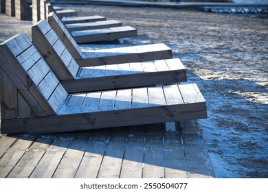 Peaceful lakeside scene featuring modern wooden benches along a boardwalk, adjacent to a sandy beach with calm water. Perfect for relaxation and enjoying nature's tranquility. - Powered by Shutterstock