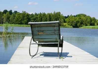 A peaceful lakeside scene featuring a rustic wooden bench on a pier, surrounded by lush greenery and calm waters, captured on a sunny summer day - Powered by Shutterstock