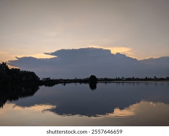 A peaceful lakeside sunset with a stunning reflection in the tranquil water. Clouds add depth, enhancing the serene atmosphere. - Powered by Shutterstock