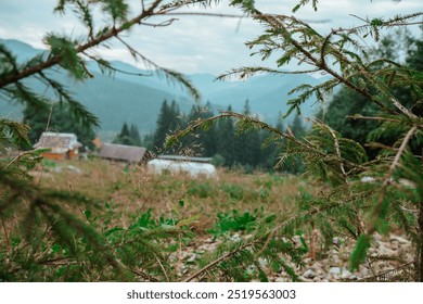 A peaceful landscape featuring rustic cabins, greenery, and distant mountains under a cloudy sky, creating a serene atmosphere. - Powered by Shutterstock