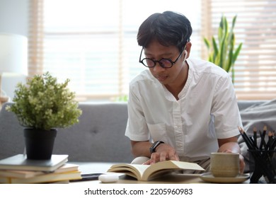 Peaceful Millennial Man Resting On Couch And Reading Book, Spending Leisure Time At Home.