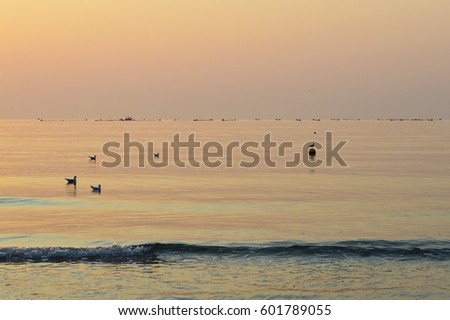 Peaceful morning by the sea at sunrise, silhouette of fish farm seen on the horizon