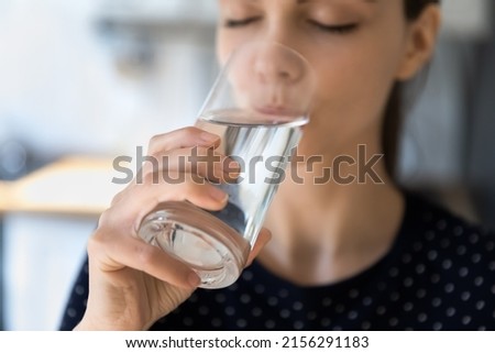 Peaceful pretty young woman with closed eyes drinking clean fresh filtered water, satisfying thirst, keeping diet, hydration balance, metabolism. Healthy lifestyle concept. Cropped shot
