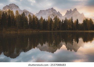 Peaceful reflections of autumnal trees and the Cadini di Misurina mountains at dawn over the calm waters of Lago d'Antorno in the Italian Dolomites. - Powered by Shutterstock