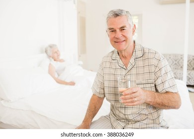 Peaceful senior man holding glass of water at home - Powered by Shutterstock