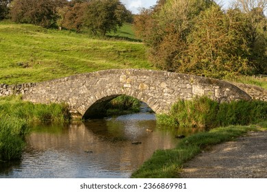 A peaceful and serene landscape in the evening sun of  a stone bridge over the river Bradford in Derbyshire - Shutterstock ID 2366869981