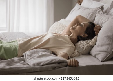 Peaceful serene mature woman enjoying leisure time in comfortable bed, lying on back over blanket, smiling with closed eyes, sleeping, taking break, pause, relaxing, breathing fresh air - Powered by Shutterstock