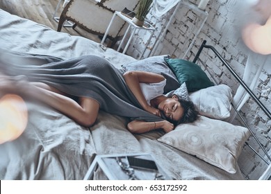 Peaceful Sleep. Top View Of Attractive Young Woman Covered With Blanket Keeping Eyes Closed And Smiling While Lying On The Bed At Home