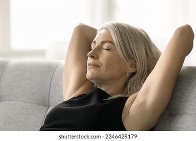 Peaceful sleepy pretty mature woman leaning on soft back of home couch, resting on sofa with closed eyes, enjoying comfort, leisure, fresh cool air, taking silent break, deep breath - Powered by Shutterstock