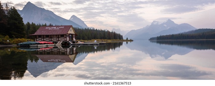 Peaceful sunrise on the bank of still alpine lake with boathouse, panorama Jasper NP, Canada