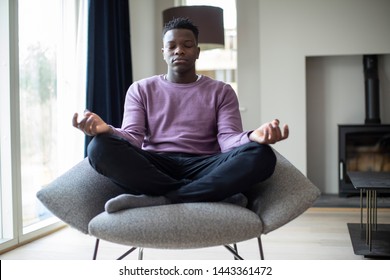 Peaceful Teenage Boy Meditating Sitting In Chair At Home