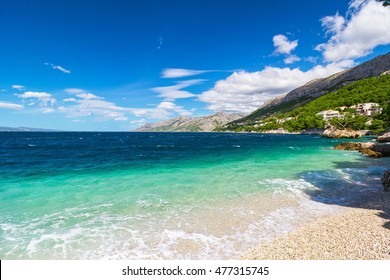 Peaceful and transparent summer blue sea, mountainous landscape in the background