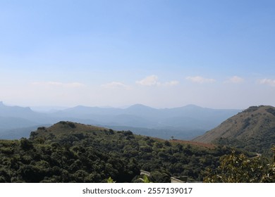 A peaceful valley stretches below, bathed in warm sunlight. Lush green fields ripple with the breeze, while distant hills frame the scene, their peaks kissed by soft clouds against a clear blue sky.

 - Powered by Shutterstock