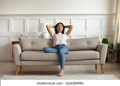Peaceful Vietnamese Millennial Girl Sit On Modern Couch In Living Room Take Nap Daydream At Home, Asian Young Woman Relax On Comfortable Sofa Furniture At Home Breathe Fresh Air, Stress Free Concept