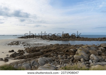 A peaceful view of a rock mass mingling with sand by the sea in Brittany, offering a calming natural scene.

