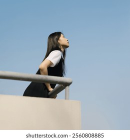 Peaceful Woman in Minimalist Urban Landscape, Gazing at Clear Blue Sky on a Tranquil Day. - Powered by Shutterstock