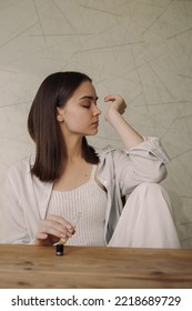 Peaceful Woman Smelling Essential Oil From Wrist While Relaxing With Closed Eyes During Aromatherapy At Home 