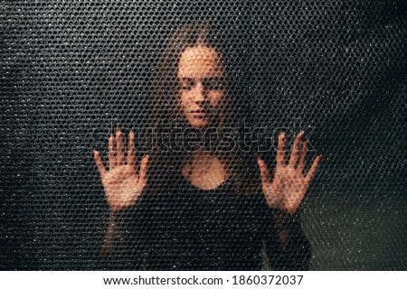 Peaceful woman. Soul healing. Spiritual practice. Esoteric mystery. Textured portrait of relaxed lady in black with closed eyes touching plastic bubble wrap wall in darkness.