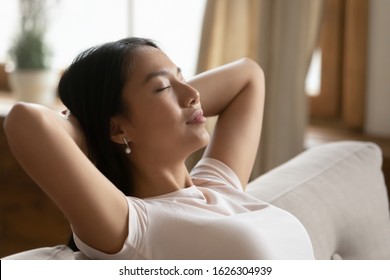 Peaceful young Asian woman relax on couch at home take nap daydream sleep in living room, calm millennial Vietnamese girl sit rest on sofa at home breathe fresh air, peace, stress free concept - Shutterstock ID 1626304939