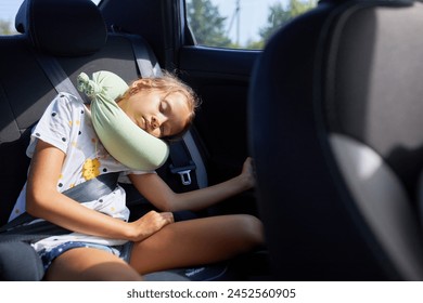 A peaceful young girl napping with a travel pillow in a vehicle, secured by a seatbelt. - Powered by Shutterstock