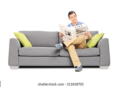 Peaceful Young Man Reading The News Seated On Sofa Isolated On White Background