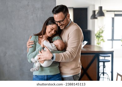 Peaceful young married couple enjoying being family, parents, holding new born baby in arms