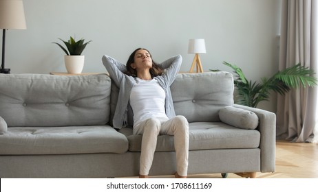 Peaceful young woman with hands behind head relaxing on cozy sofa at home, daydreaming and meditating, satisfied serene girl leaning back, stretching on comfortable couch in living room - Shutterstock ID 1708611169