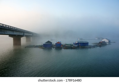 Peacefull landscape of fishing village in fog with hamlet have group of house on surface water, big concrete bridge cross the lake, atmosphere full of misty make romantic of Vietnam country