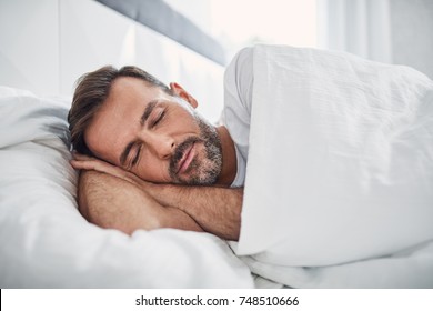 Peacefulness concept. Handsome man sleeping in bed