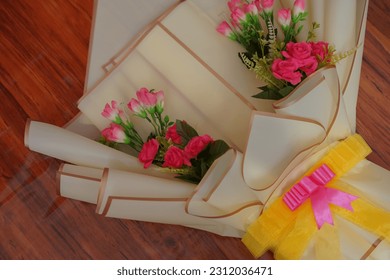 Peach bouquet with artificial roses and yellow ribbon on a wood pattern rug - Shutterstock ID 2312036471